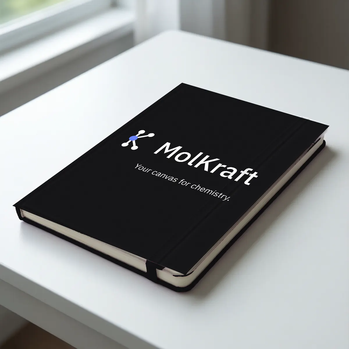 A black hardcover notebook with the MolKraft logo and Your canvas for chemistry in white.
