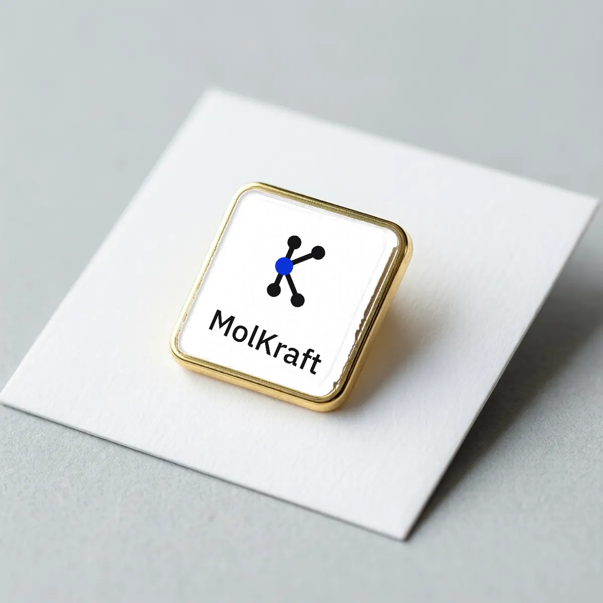 A square gold-edged enamel pin with the MolKraft K logo and wordmark.